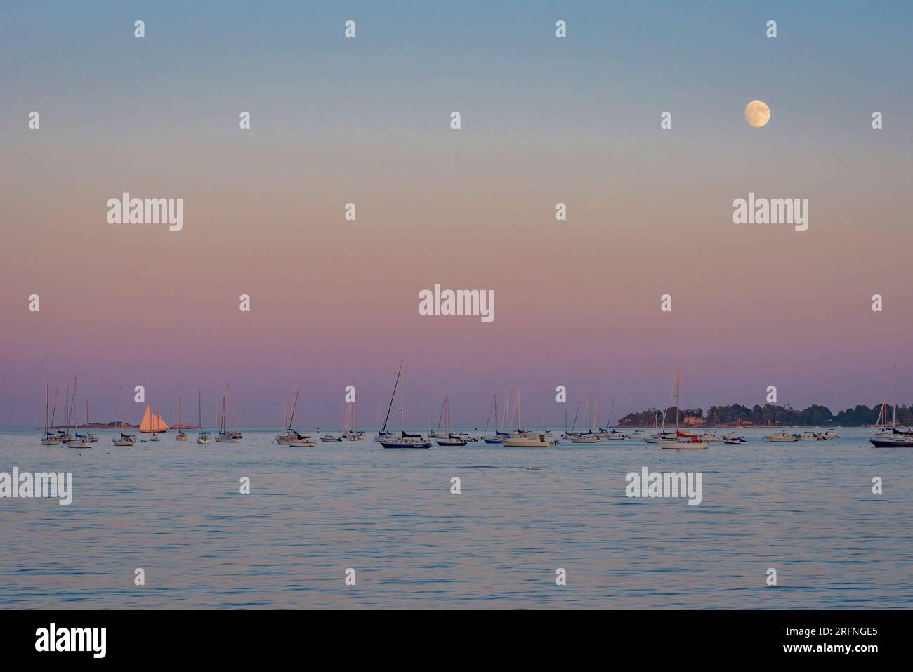 Ceretta Gibbous Sturgeon Moon che si innalza sul Canale con il pastello Rainbow Sky Foto Stock