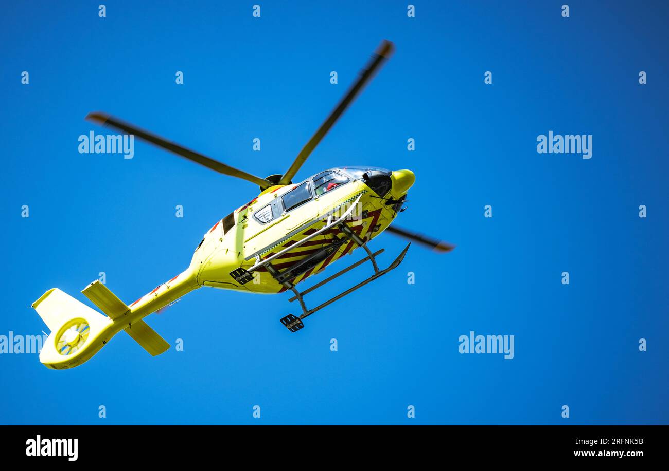 Elicottero giallo Ambulance che riceve una chiamata di emergenza. Cielo azzurro. Foto Stock