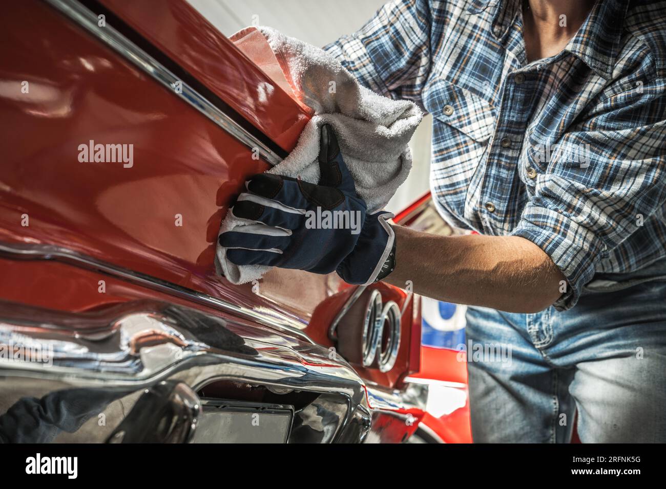 Cameriere Caucasico addetto al restauro di auto classiche che pulisce uno dei veicoli Foto Stock