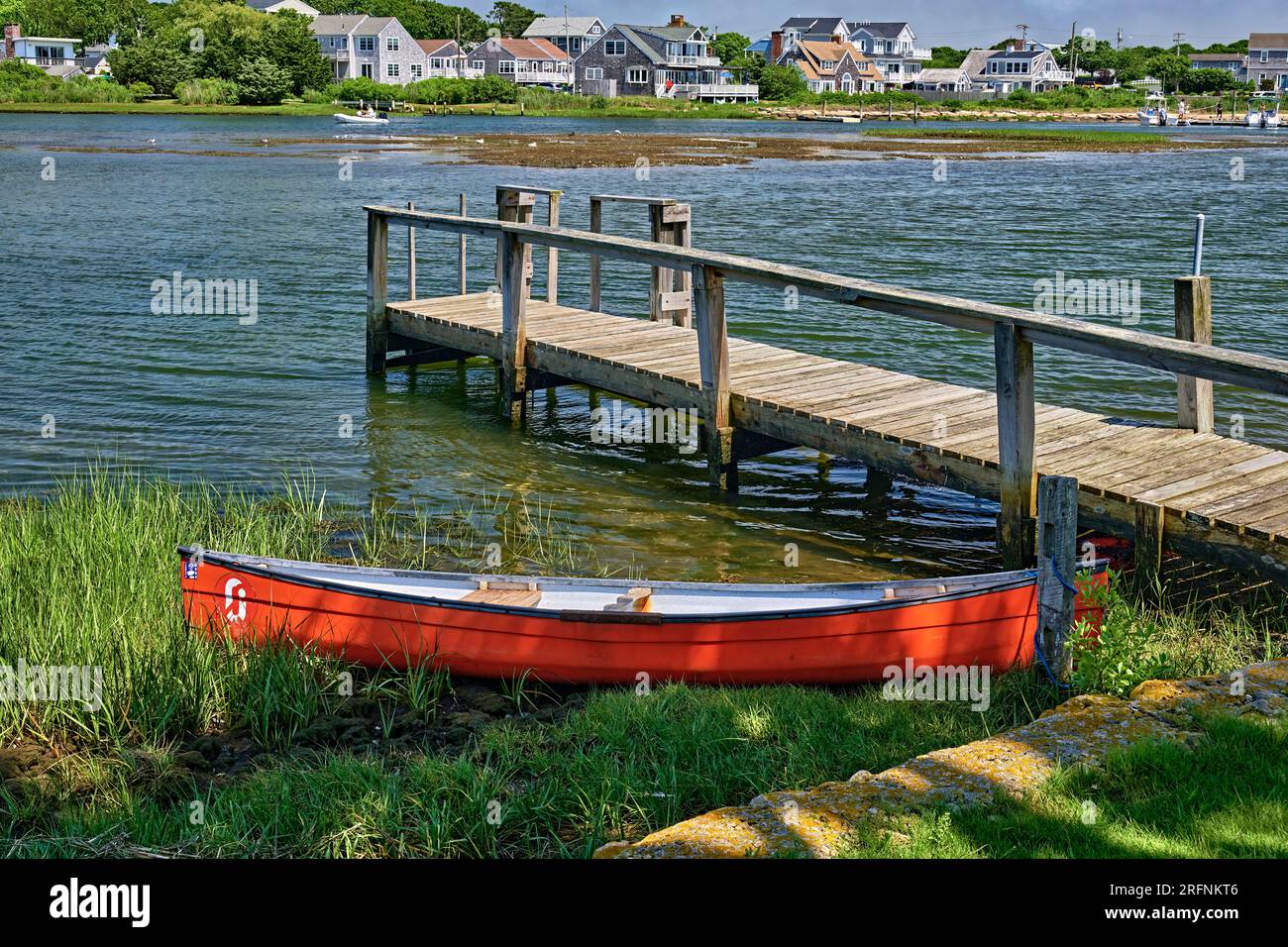 Un'arancia, kayak boat. Seduto sulla terraferma a un molo con la bassa marea. All'entrata del porto interno a Lewis Bay presso Colonial Beach. A Cape Cod, ma. Foto Stock