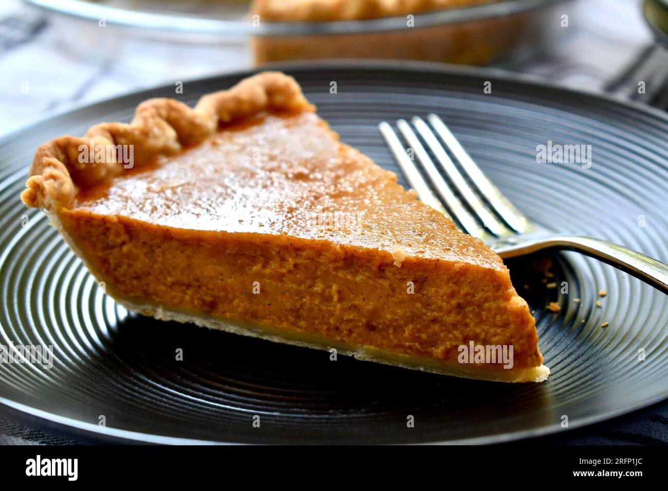 Una fetta di torta di zucca su un piatto nero Foto Stock
