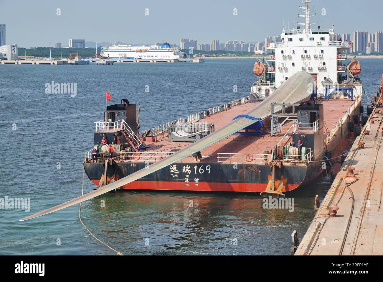 YANTAI, CINA - 4 AGOSTO 2023 - Una nave da carico che trasporta pale eoliche offshore di grandi dimensioni B1260A ormeggia nell'area del porto di Penglai nel porto di Yantai, Shan Foto Stock
