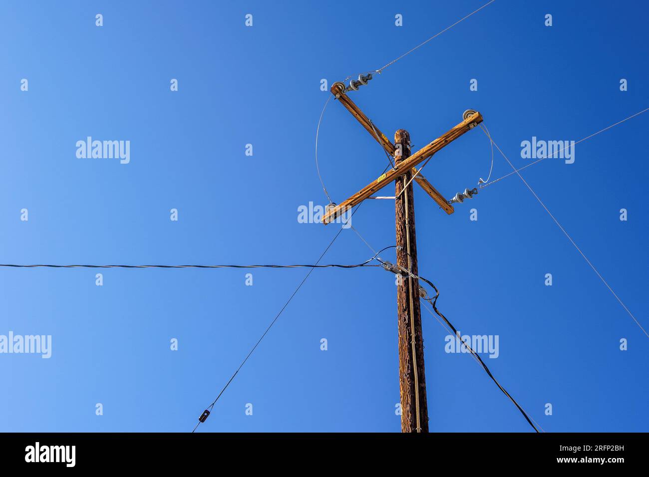 Un vecchio palo elettrico in legno con fili e un cielo blu cristallino a Joshua Tree, California. Foto Stock