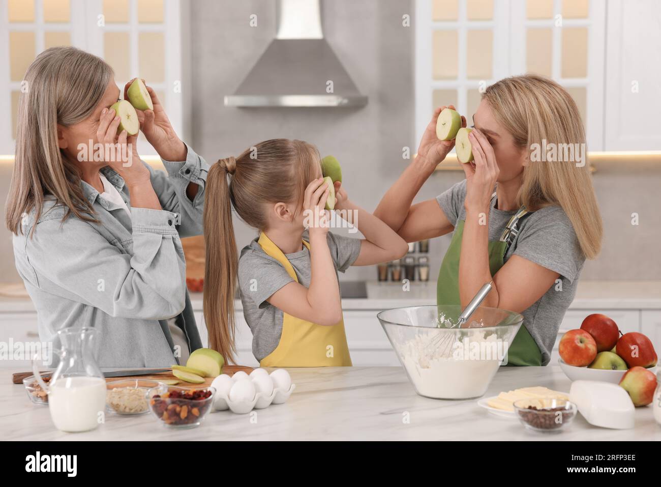 Tre generazioni. La nonna felice, sua figlia e sua nipote si divertono mentre cucinano insieme in cucina Foto Stock