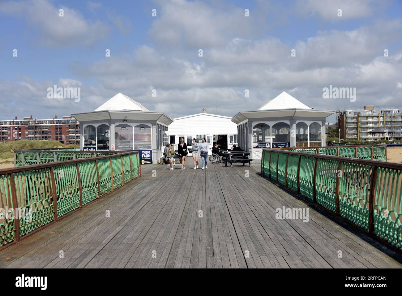 La gente si gode una passeggiata fino alla fine del breve molo a St Annes on Sea, Lancashire, Regno Unito. Giovani donne che camminano. Una persona in sedia a rotelle. Foto Stock