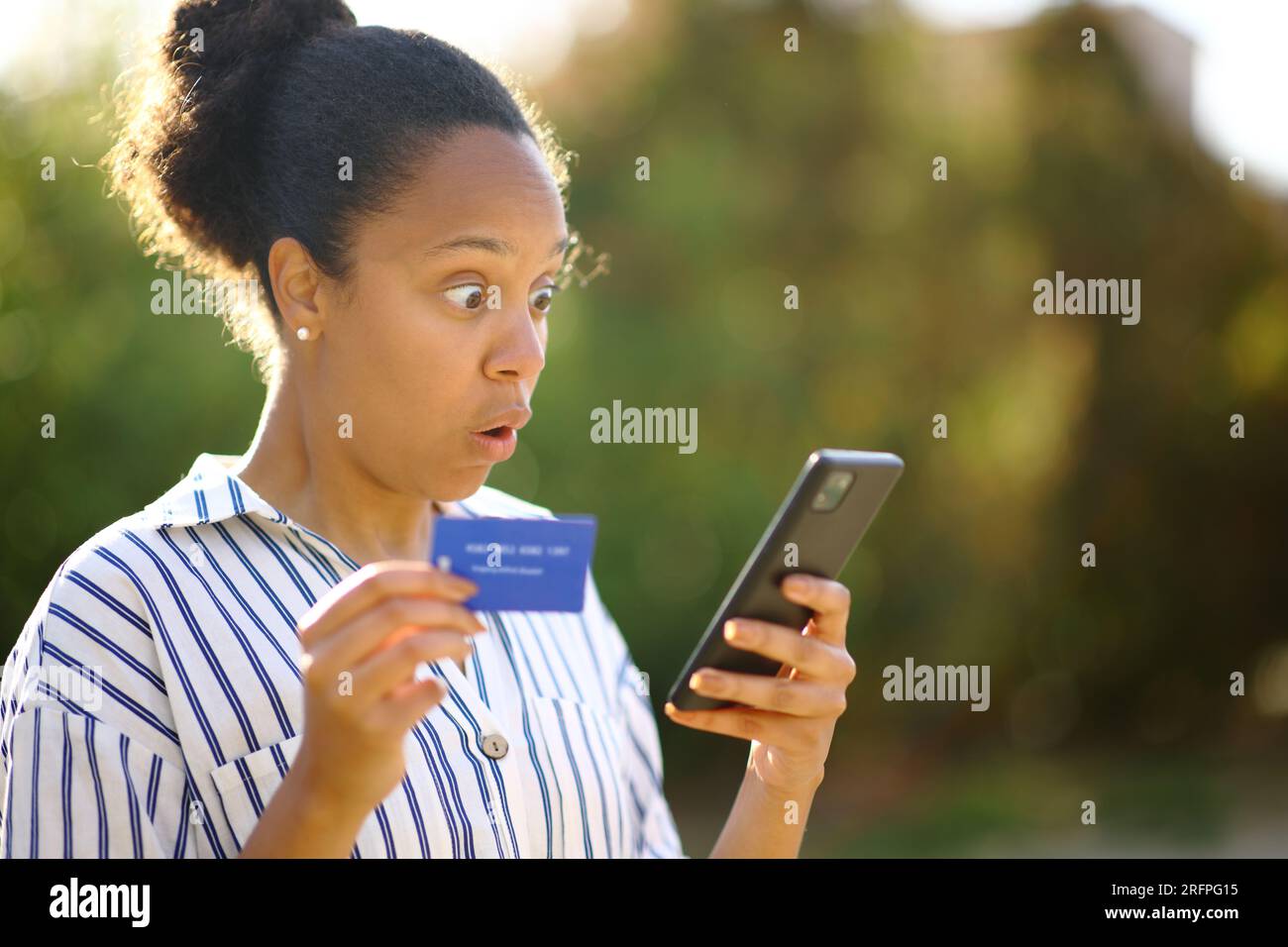 Ha sorpreso l'acquirente nero che usa il telefono e la carta di credito per acquistare online in un parco Foto Stock