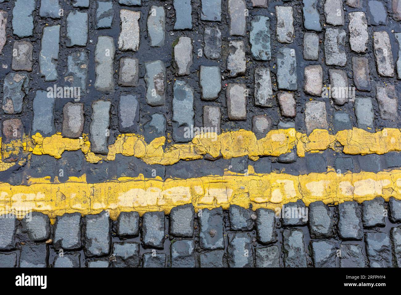 Due linee gialle su strada acciottolata, primo piano Foto Stock