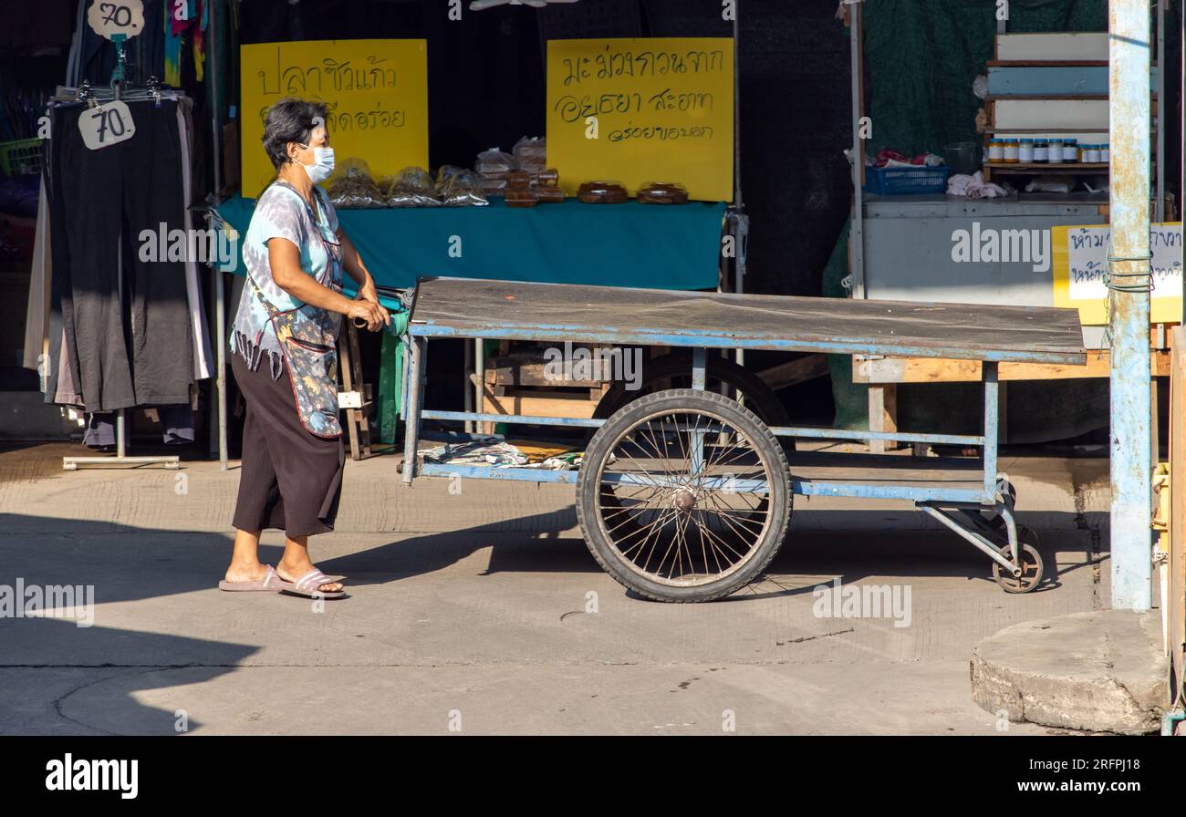 SAMUT PRAKAN, THAILANDIA, 02 2023 FEBBRAIO, Una donna spinge un tavolo mobile - carrello sul mercato Foto Stock