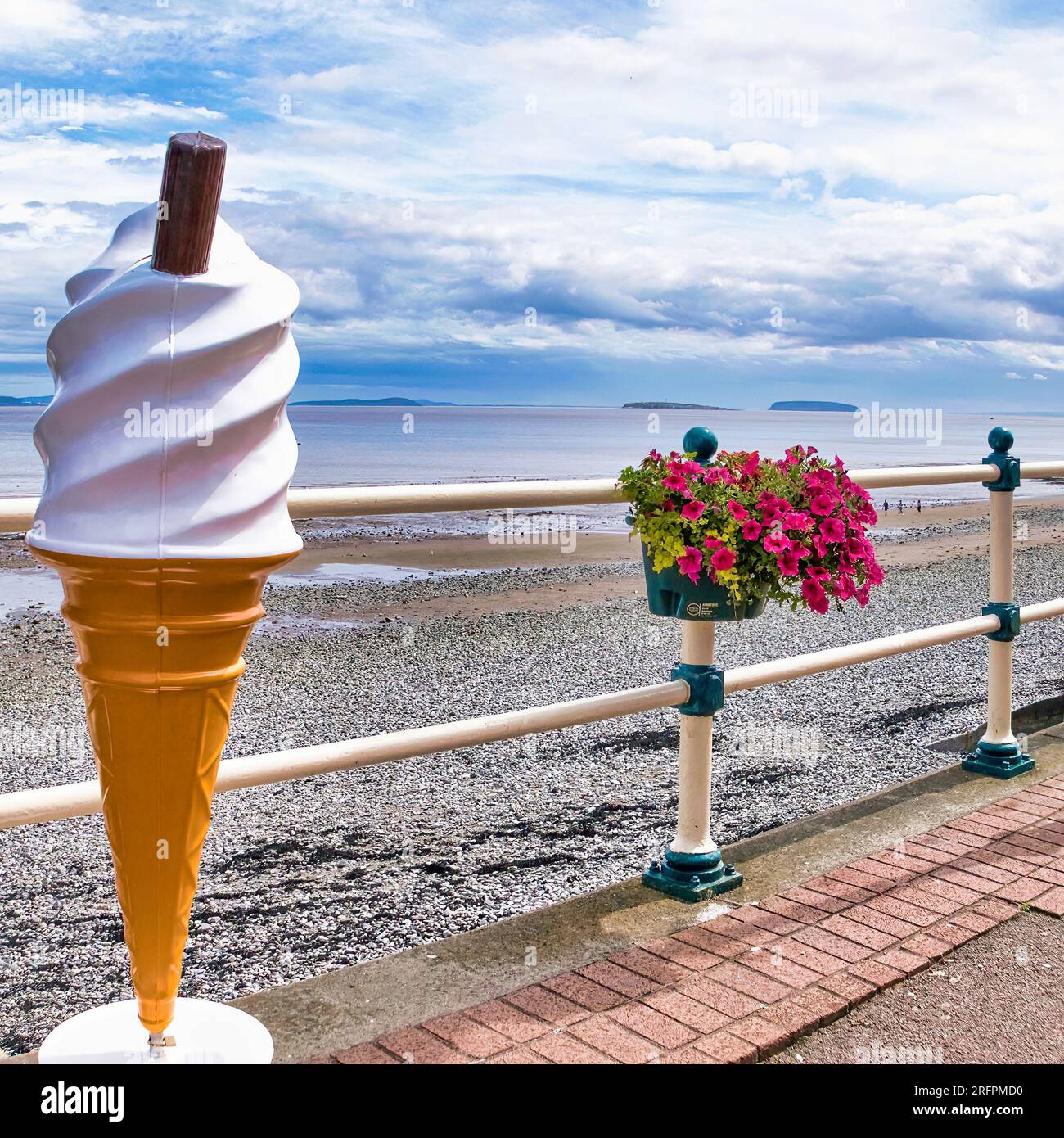 Un gigantesco cono gelato di plastica sul lungomare in un pomeriggio nuvoloso. Signor Whippy. Fiori. Pavimentazione. 99 Flake. Foto Stock
