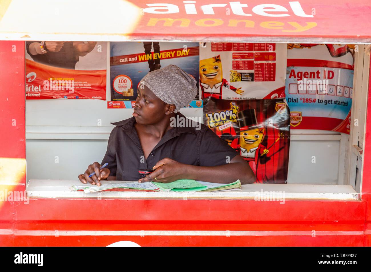 Venditore di carte telefoniche nella sua bancarella al mercato Jinja, in Uganda. Foto Stock