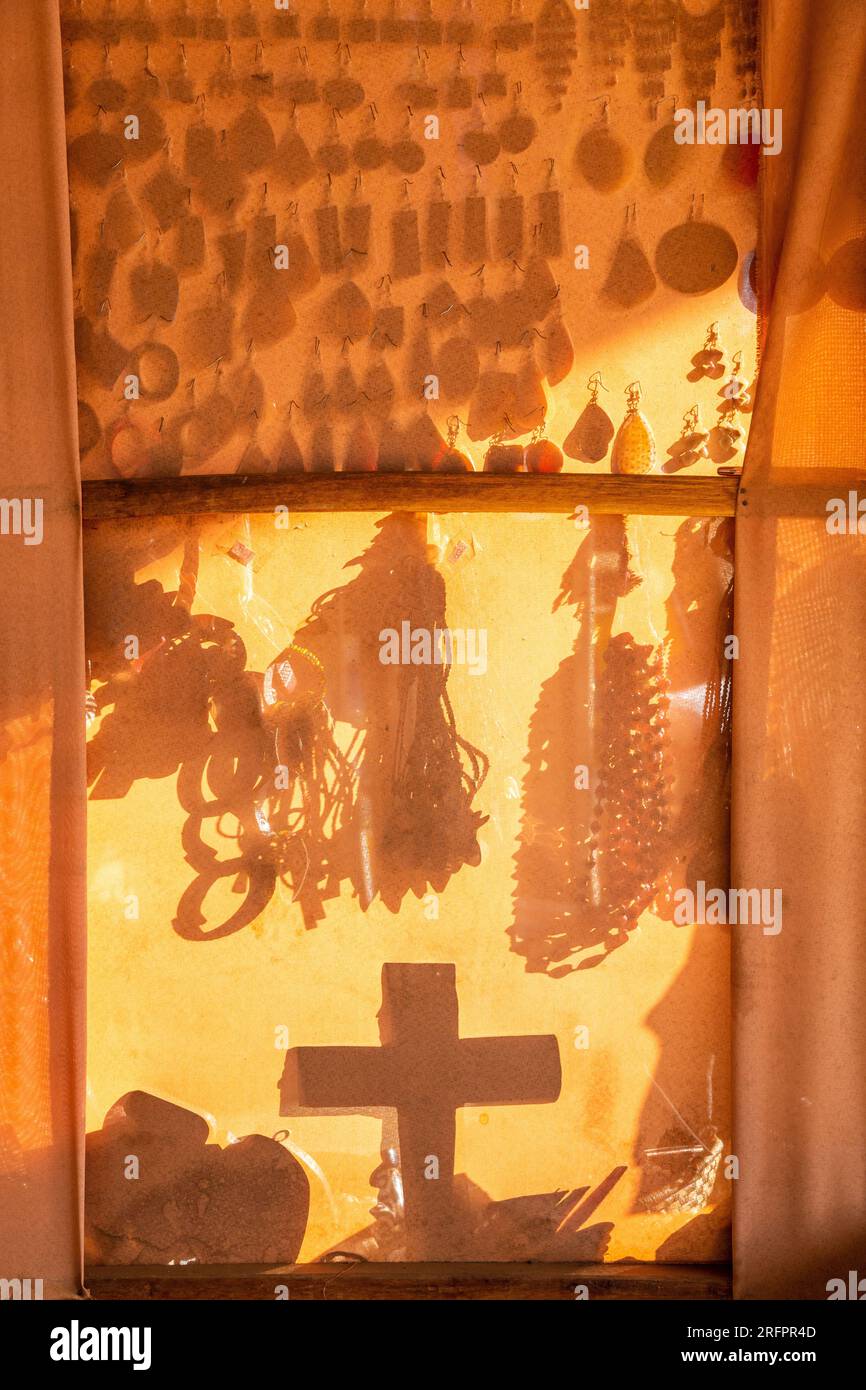 Mostra di un commerciante di ciondoli, ciondoli e bigiotteria visti in modo trasparente attraverso una tela. Foto Stock