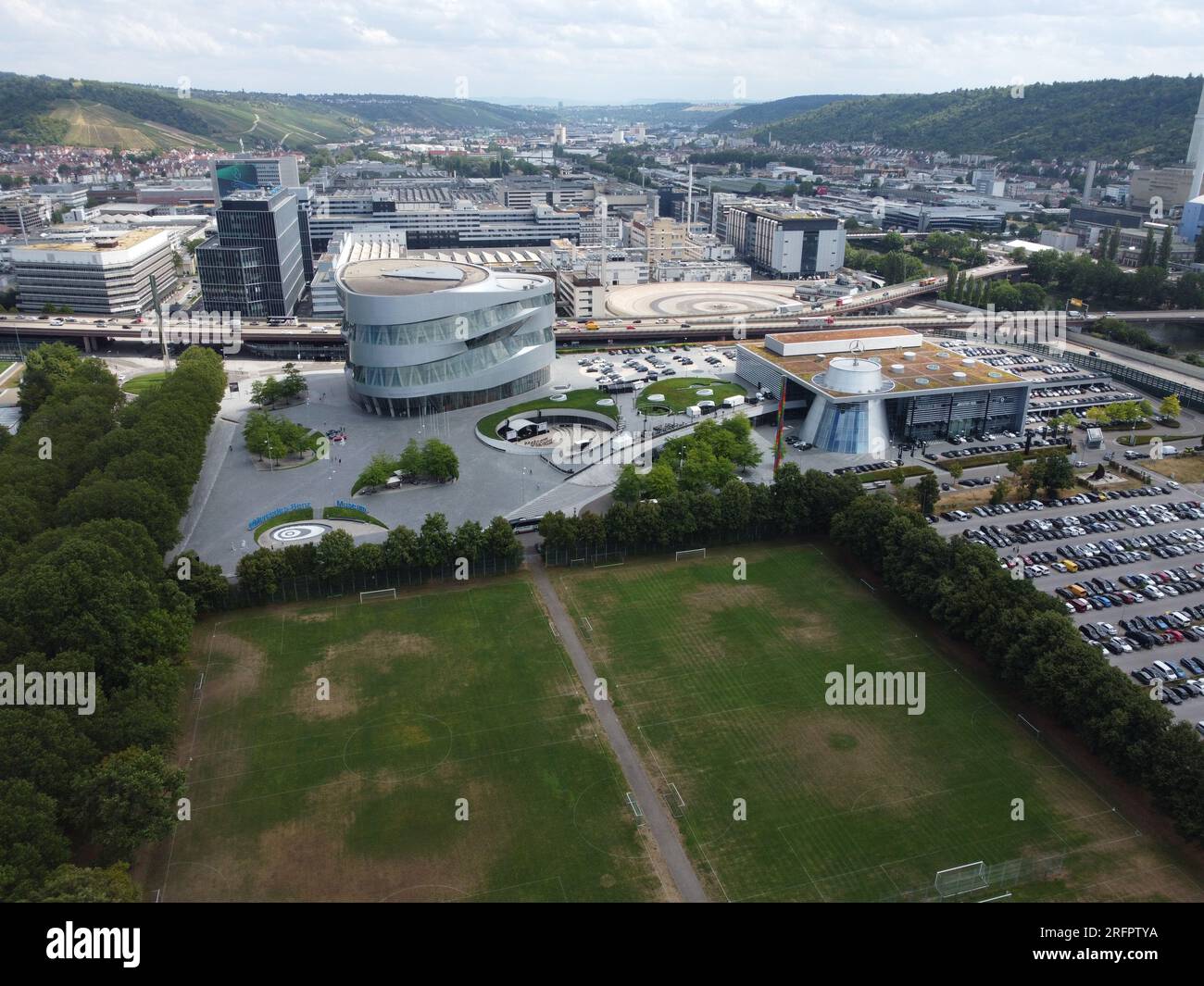Stoccarda, Baden-Württemberg, Germania - 12 luglio 2023: Veduta aerea del Museo Mercedes-Benz in primo piano e dello stabilimento di Untertürkheim nel bac Foto Stock