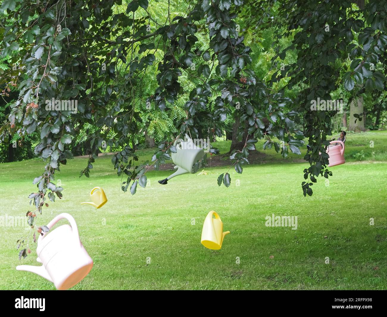 innaffiare lattine pendono da un albero sopra un prato per simboleggiare la scarsità d'acqua Foto Stock
