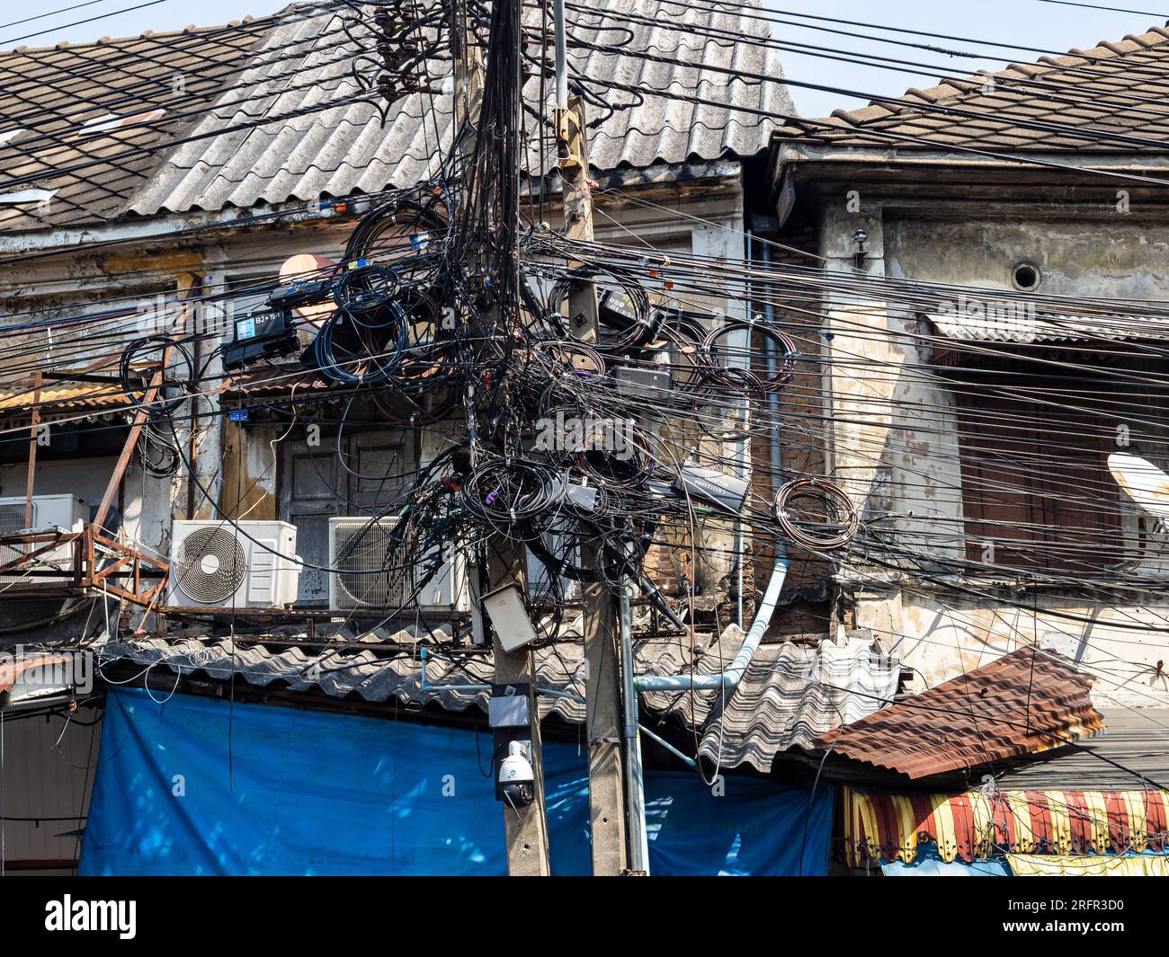 A Bangkok, in Thailandia, un impianto elettrico presenta una caotica serie di cavi aggrovigliati. Foto Stock