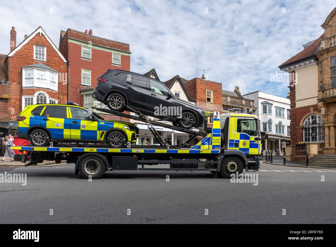 Un autocarro della polizia che attraversa il centro di Marlborough, Wiltshire, Inghilterra, Regno Unito, che trasporta un'auto sequestrata Foto Stock