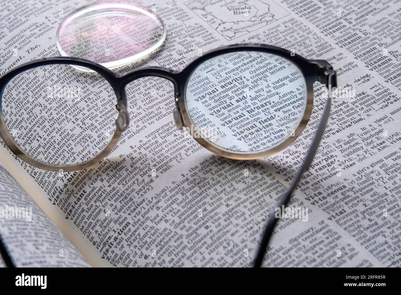 STILL Life di un paio di occhiali da vista con una lente mancante in cima a un dizionario inglese, 2023, USA Foto Stock