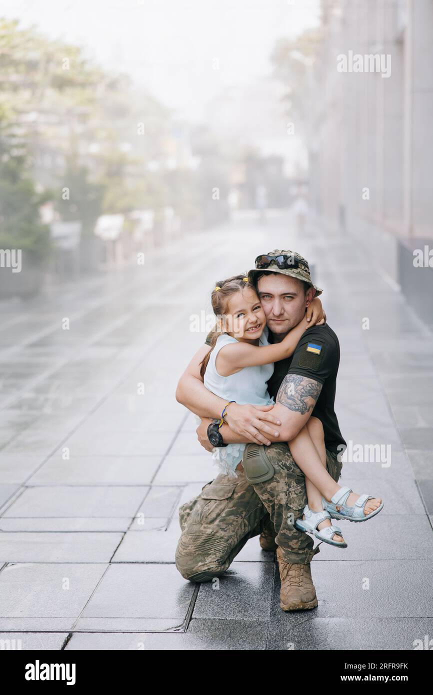 La piccola ragazza Ucraina incontra suo padre dalla guerra durante le sue vacanze e Joyful lo abbraccia. Guerra in Ucraina. Invasione militare russa in Ucraina. Foto Stock