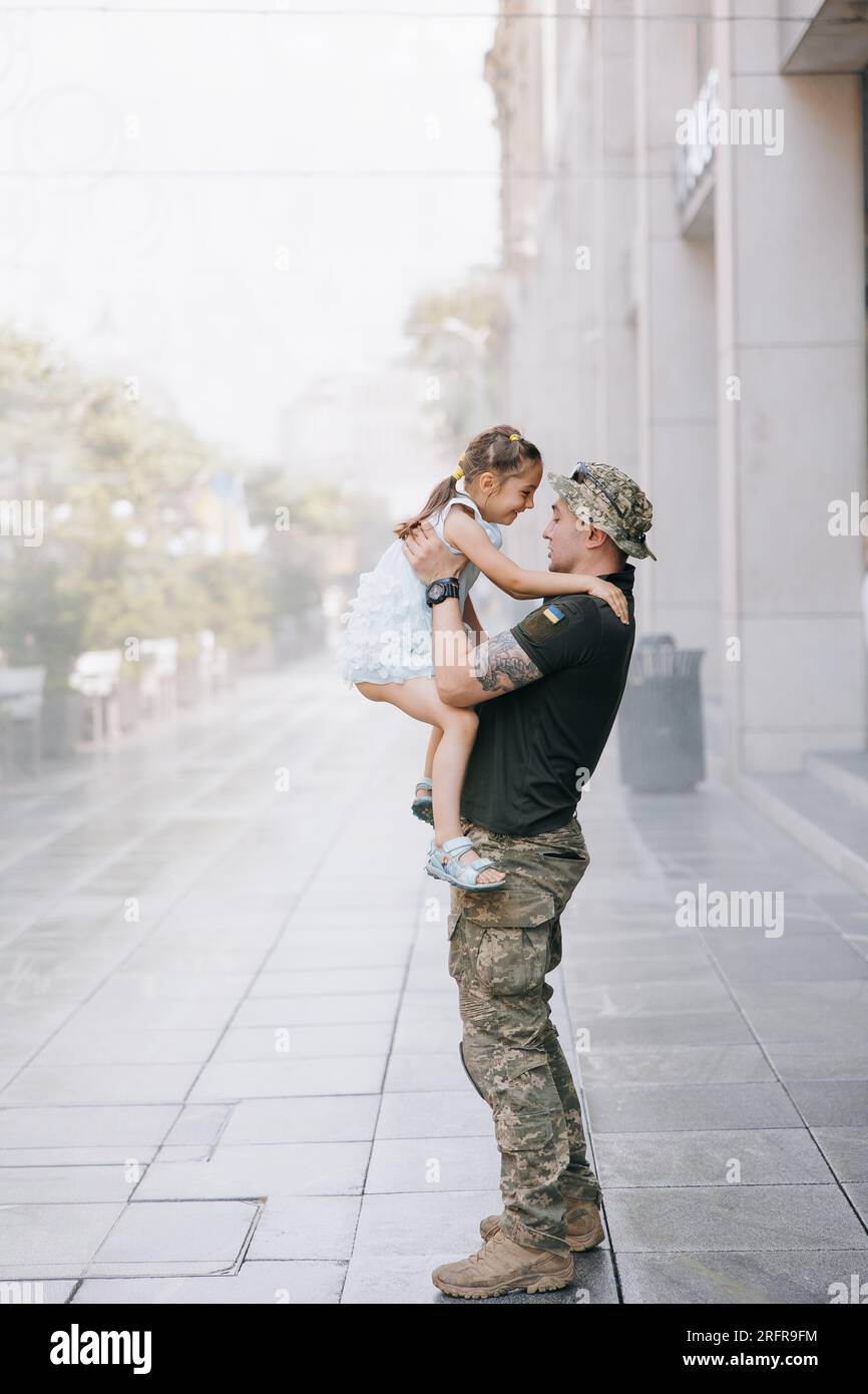 La piccola ragazza Ucraina incontra suo padre dalla guerra durante le sue vacanze e Joyful lo abbraccia. Guerra in Ucraina. Invasione militare russa in Ucraina. Foto Stock
