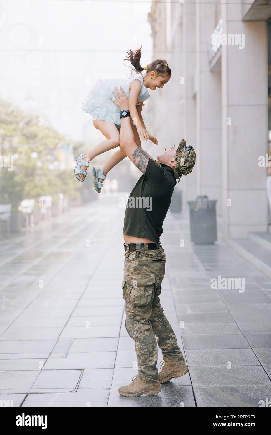Il soldato ucraino di ritorno dalla guerra incontra la sua figlia e Joyful getta il bambino. Guerra in Ucraina. Invasione militare russa in Ucraina Foto Stock