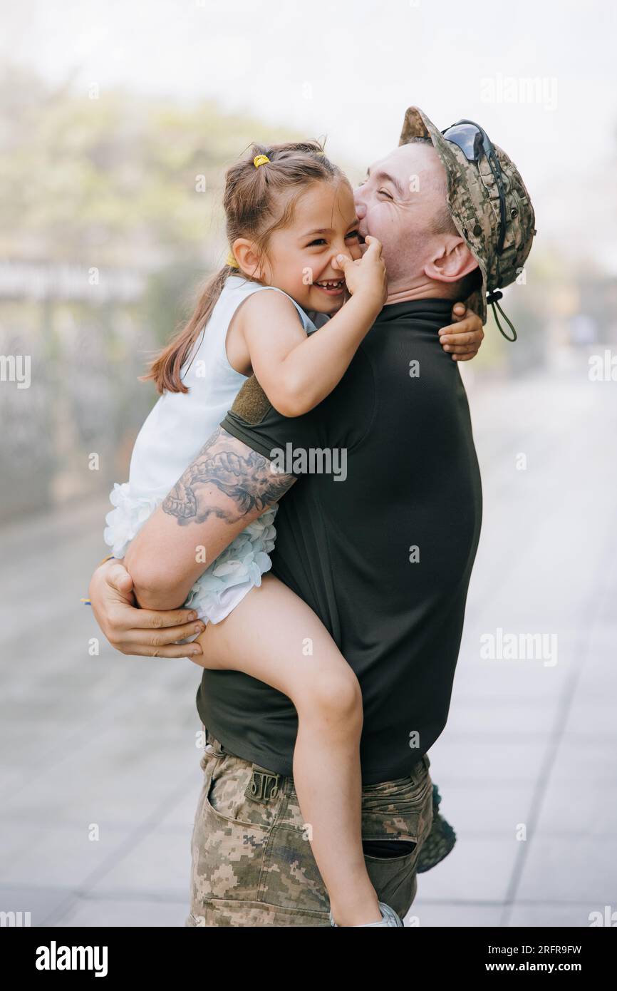 Il soldato ucraino di ritorno dalla guerra incontra la sua piccola figlia e Joyful la abbraccia. Guerra in Ucraina. Invasione militare russa in Ucraina. Guerra Foto Stock