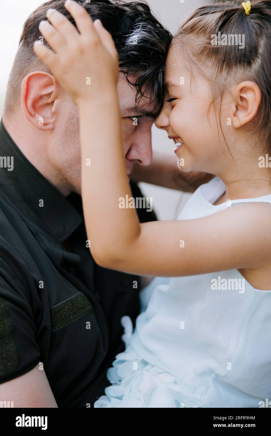 Ritratto della bambina Ucraina che incontra suo padre durante la guerra durante le sue vacanze e gioiosa lo abbraccia. Guerra in Ucraina. Invasi militare russa Foto Stock