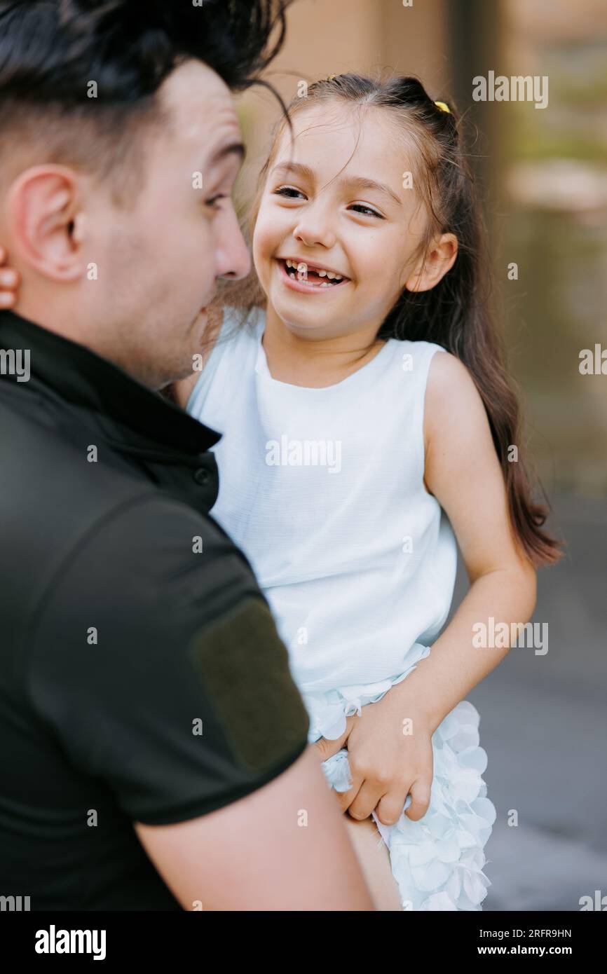 Ritratto della bambina Ucraina che incontra suo padre durante la guerra durante le sue vacanze e gioiosa lo abbraccia. Guerra in Ucraina. Invasi militare russa Foto Stock