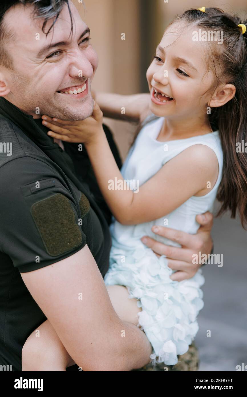 Ritratto di un felice soldato ucraino di ritorno dalla guerra incontrando la sua figlia e Joyful la abbraccia. Guerra in Ucraina. Invas militari russe Foto Stock