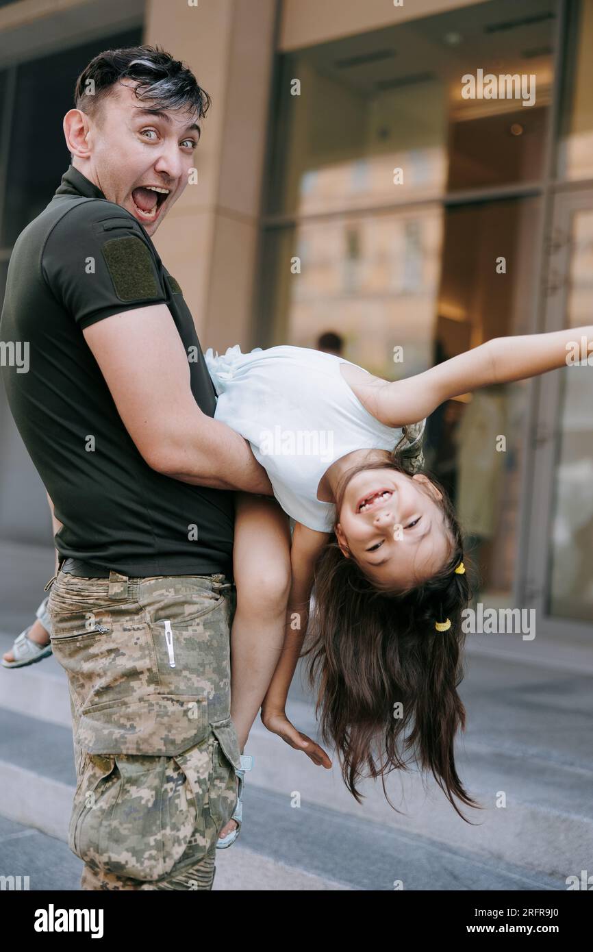 La bambina Ucraina incontra suo padre durante la guerra durante le sue vacanze e gioisce allegramente con lui. Guerra in Ucraina. Invasione militare russa a Ukra Foto Stock