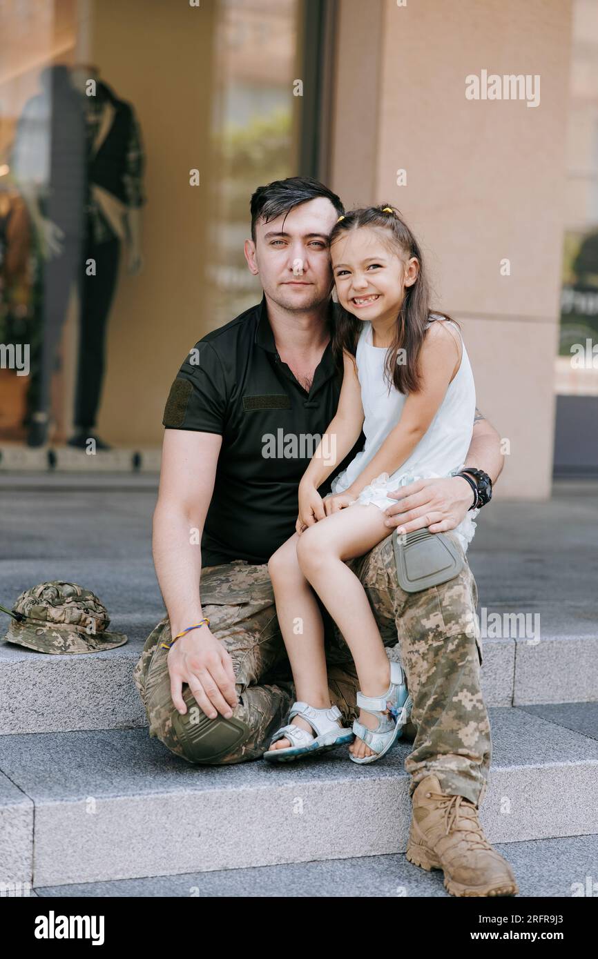 Il soldato ucraino di ritorno dalla guerra incontra la sua piccola figlia felice e la abbraccia. Guerra in Ucraina. Invasione militare russa in Ucraina. Guerra a Foto Stock