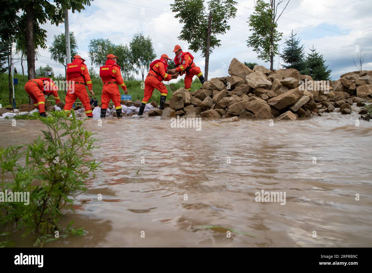 (230805) -- HARBIN, 5 agosto 2023 (Xinhua) -- i vigili del fuoco trasferiscono rocce per bloccare le inondazioni vicino al villaggio di Dawan del distretto di Dong'an, Mudanjiang, provincia di Heilongjiang nella Cina nordorientale, 5 agosto 2023. Innescato da piogge torrenziali nella città di Mudanjiang e nella capitale provinciale Harbin, i livelli dell'acqua di alcuni fiumi hanno superato il livello dell'acqua di avvertimento. Squadre di soccorso di emergenza, tra cui vigili del fuoco locali e vigili del fuoco forestale, sono stati inviati per aiutare con il lavoro di soccorso e soccorso. Le pattuglie di 24 ore sugli argini sono state condotte per controllare i rischi, e le inondazioni colpite r Foto Stock