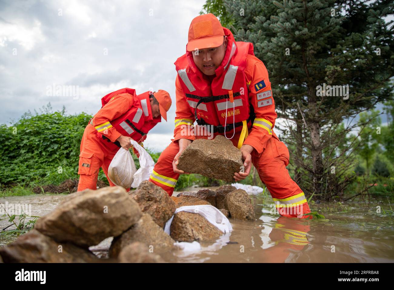 (230805) -- HARBIN, 5 agosto 2023 (Xinhua) -- i vigili del fuoco trasferiscono rocce per bloccare le inondazioni vicino al villaggio di Dawan del distretto di Dong'an, Mudanjiang, provincia di Heilongjiang nella Cina nordorientale, 5 agosto 2023. Innescato da piogge torrenziali nella città di Mudanjiang e nella capitale provinciale Harbin, i livelli dell'acqua di alcuni fiumi hanno superato il livello dell'acqua di avvertimento. Squadre di soccorso di emergenza, tra cui vigili del fuoco locali e vigili del fuoco forestale, sono stati inviati per aiutare con il lavoro di soccorso e soccorso. Le pattuglie di 24 ore sugli argini sono state condotte per controllare i rischi, e le inondazioni colpite r Foto Stock