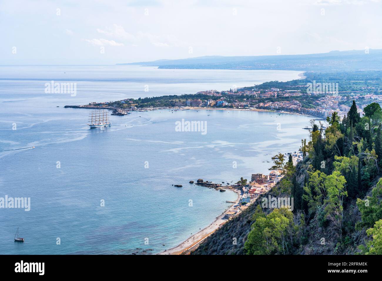 Vista verso il basso sulla Baia di Naxos e la famosa località turistica di Giardini Naxos da Taormina in Sicilia, Italia Foto Stock
