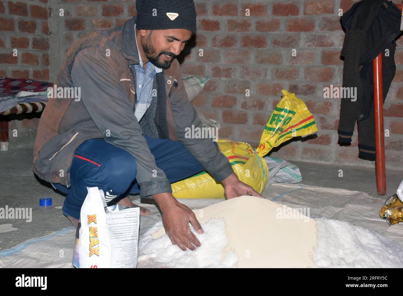 09-12-2021 Indore, Madhya Pradesh, India. Agricoltore indiano che mescola diversi elementi fertilizzanti nel letame, a casa. messa a fuoco selettiva Foto Stock