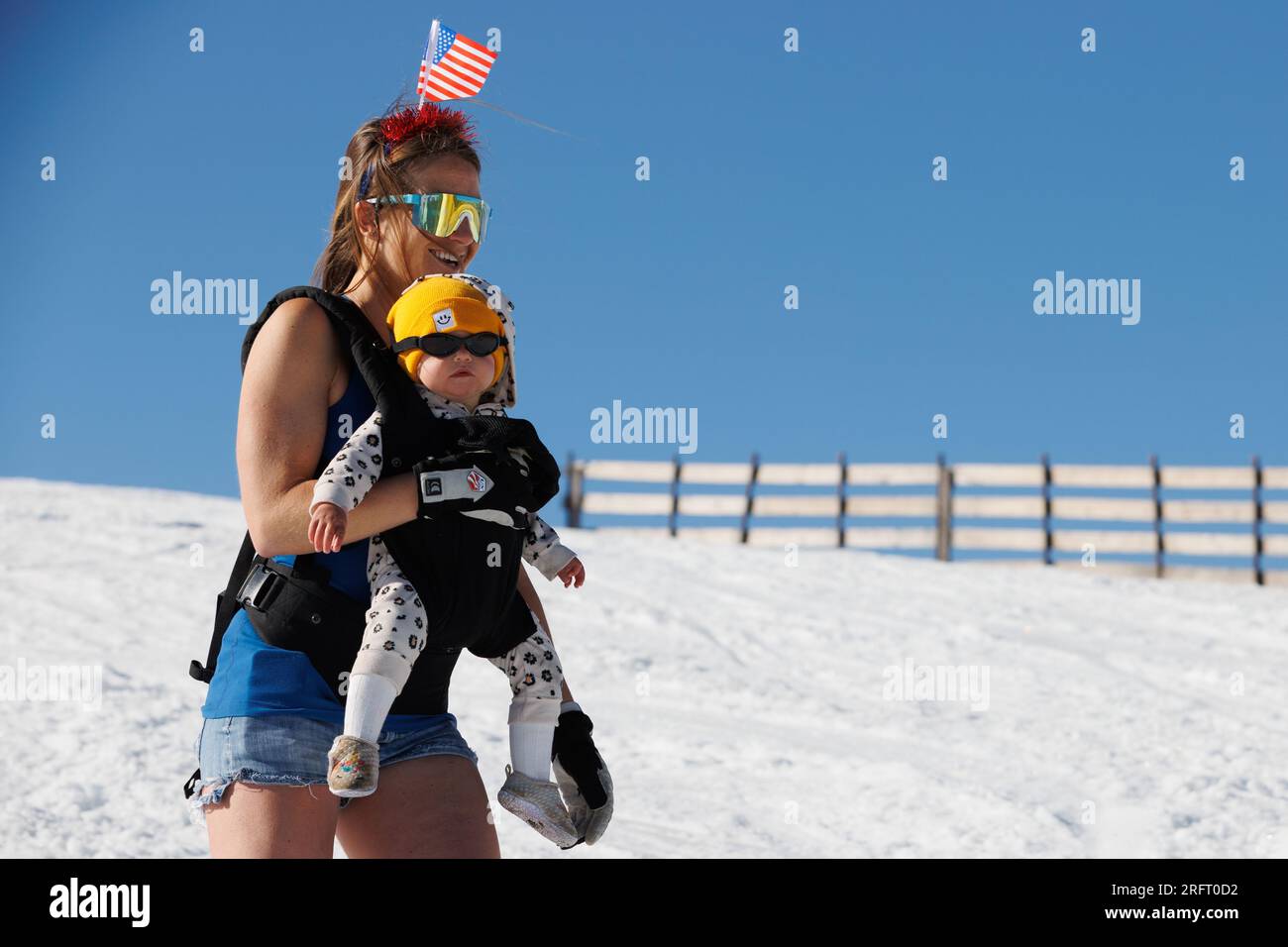 Mammoth Lakes, CA. 4 luglio 2023. Una donna sciistica con un bambino e una bandiera americana sulla testa al Mammoth Mountain Ski Resort in una limpida giornata estiva. Foto Stock