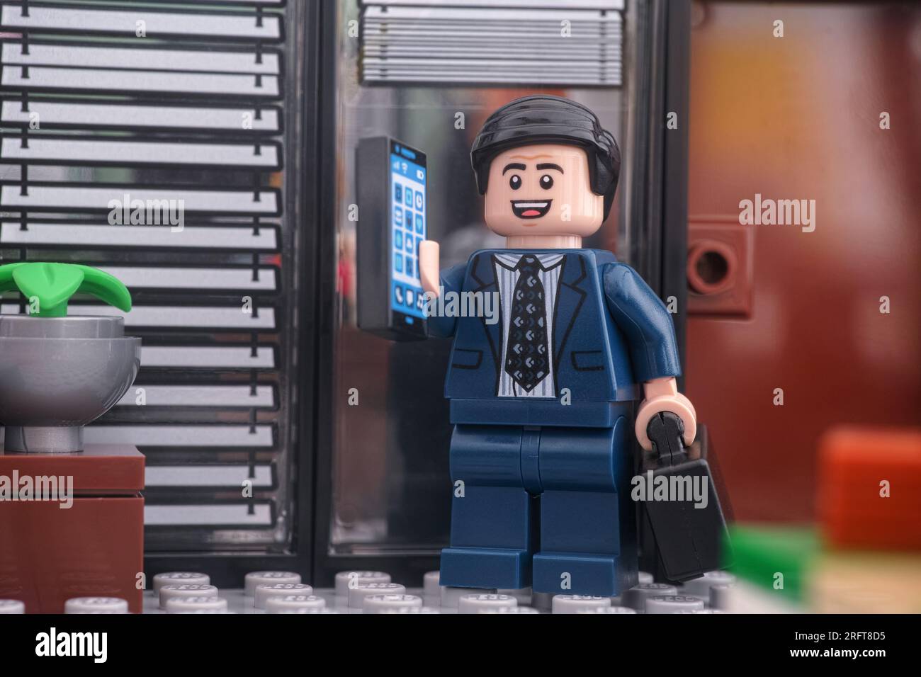 Tambov, Federazione Russa - 4 agosto 2023 Una minifigura di un uomo d'affari Lego in piedi davanti alla porta di un ufficio e rispondendo al cellulare. Foto Stock
