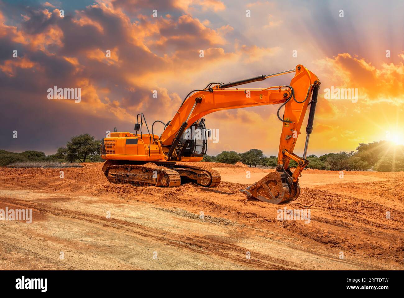 escavatore giallo sul cantiere al tramonto Foto Stock