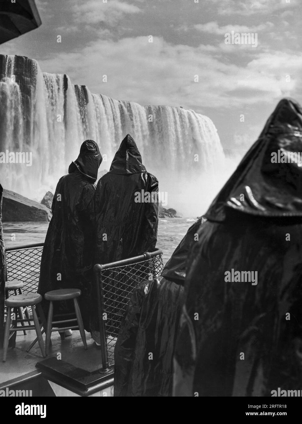Cascate del Niagara, New York: 17 maggio 1937 due sposi in luna di miele, immersi in pelli di petrolio per evitare di essere inzuppati dallo spray, guardano verso le maestose cascate Horseshoe dal ponte del tour in barca "Maid of the Mist" durante il suo primo viaggio del 1937. Foto Stock