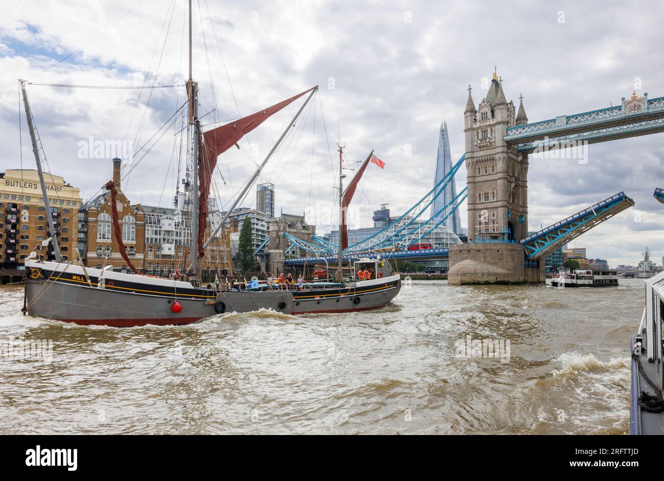 La chiatta a vela del Tamigi passerà sotto il Tower Bridge aperto presso Butlers Wharf, Bermondsey, nella Docklands Pool di Londra Foto Stock