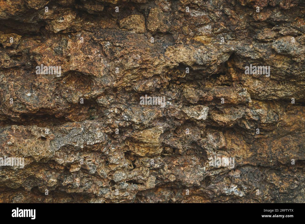 Sfondo di pietra, parete di roccia sullo sfondo con tessitura grossolana. Abstract, grungy e superficie testurizzata del materiale lapideo. La natura particolare delle rocce. Foto Stock