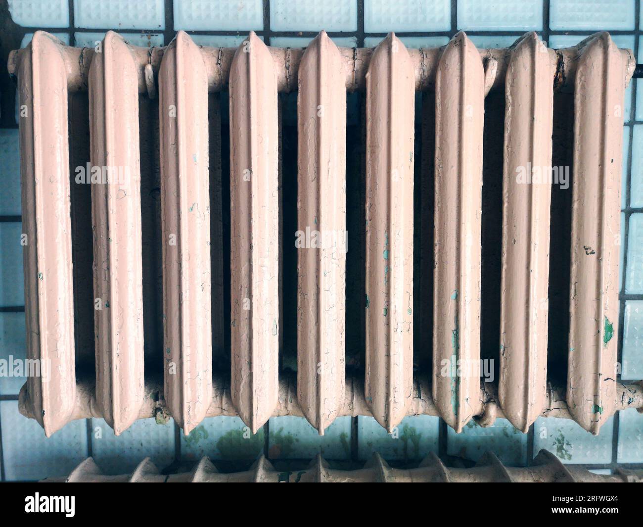 Vecchio radiatore sulla vecchia parete sporca. Radiatore di riscaldamento retrospettivo Foto Stock