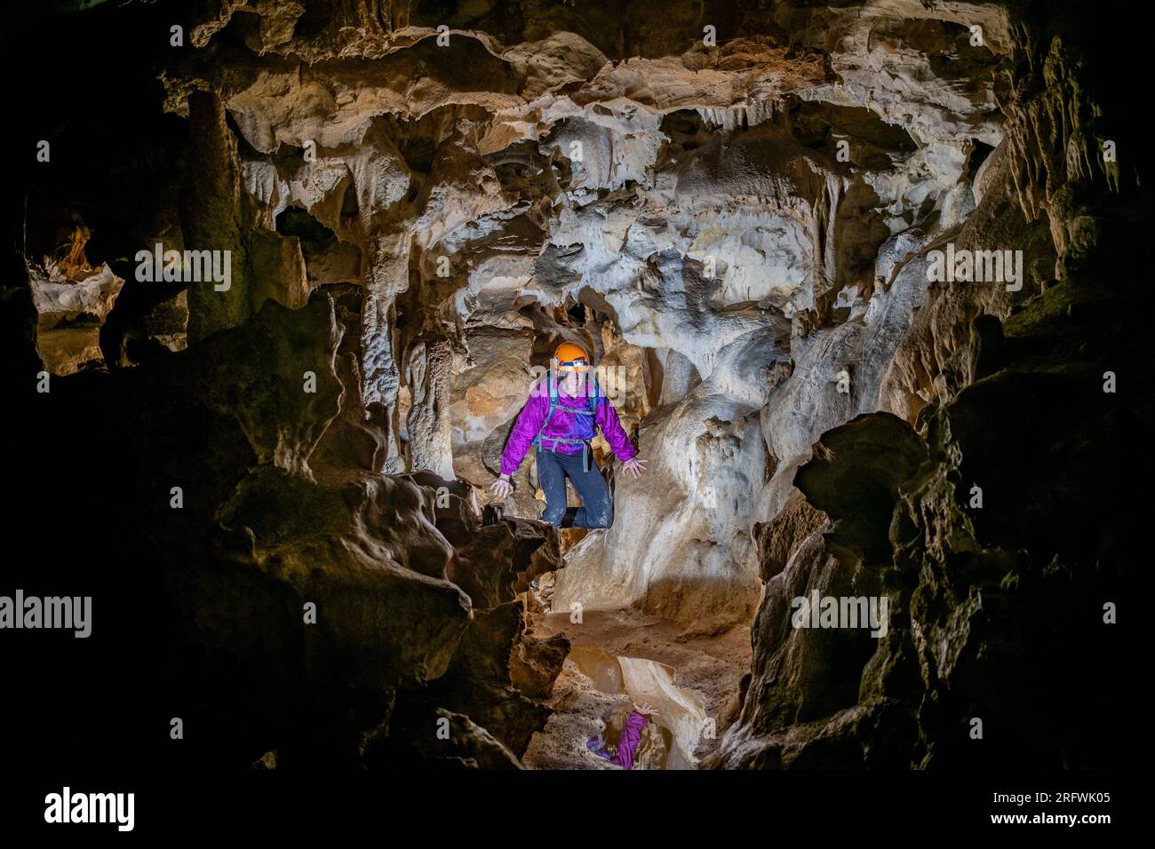 Giovane donna che si tuffa in una caverna. Concetto di femminismo. Concetto di sport femminile. Foto Stock