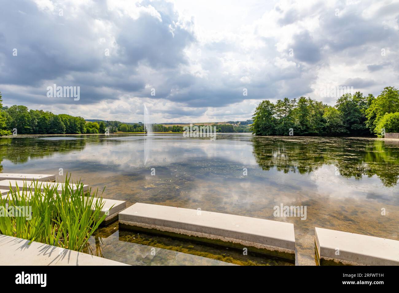 Lago di Echternach con piattaforme in cemento sulle rive, getto d'acqua che sgorga dalla fontana e alberi verdi sullo sfondo, riflesso sulla superficie dell'acqua, pennsylvania Foto Stock