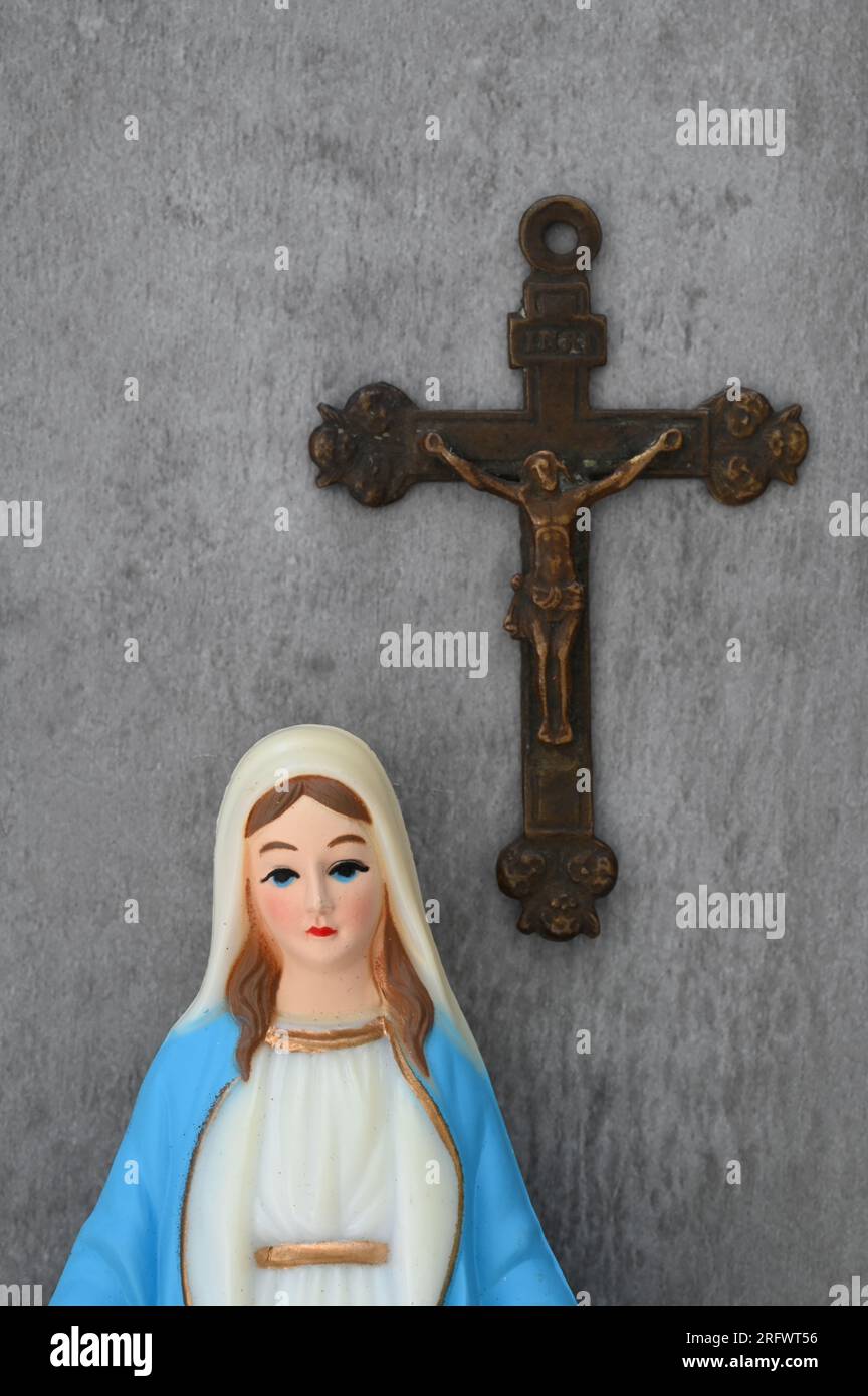 Modello della Vergine Maria con grandi occhi blu che sembrano tristi e indossa vestaglia blu con crocifisso dietro di lei Foto Stock