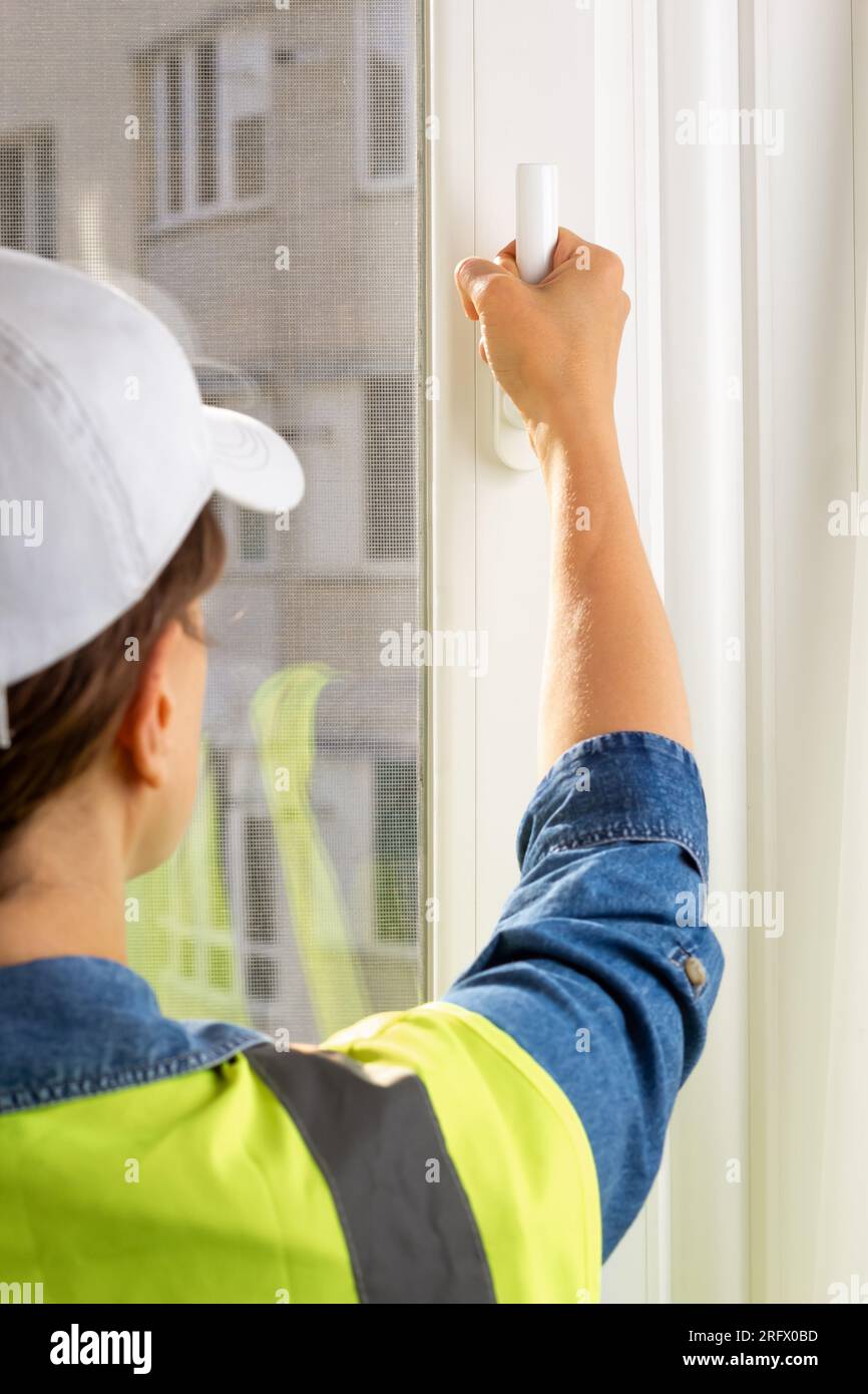 Donna costruttore ripara maniglie per finestre in plastica. Foto Stock