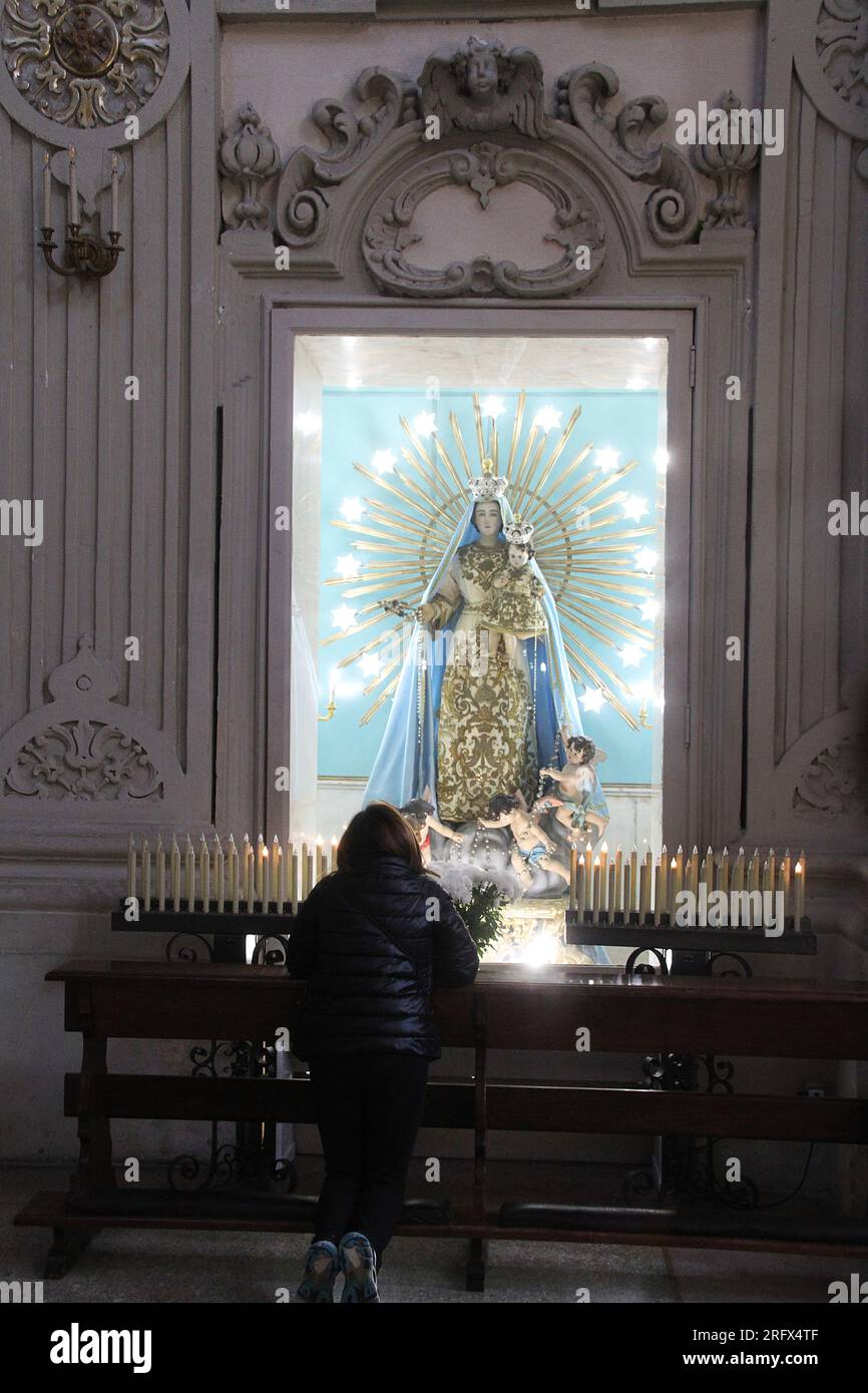 Lecce, Italia. Interno della Basilica di S. Giovanni Battista al Rosario. Donna che prega davanti alla statua di nostra Signora del Rosario. Foto Stock
