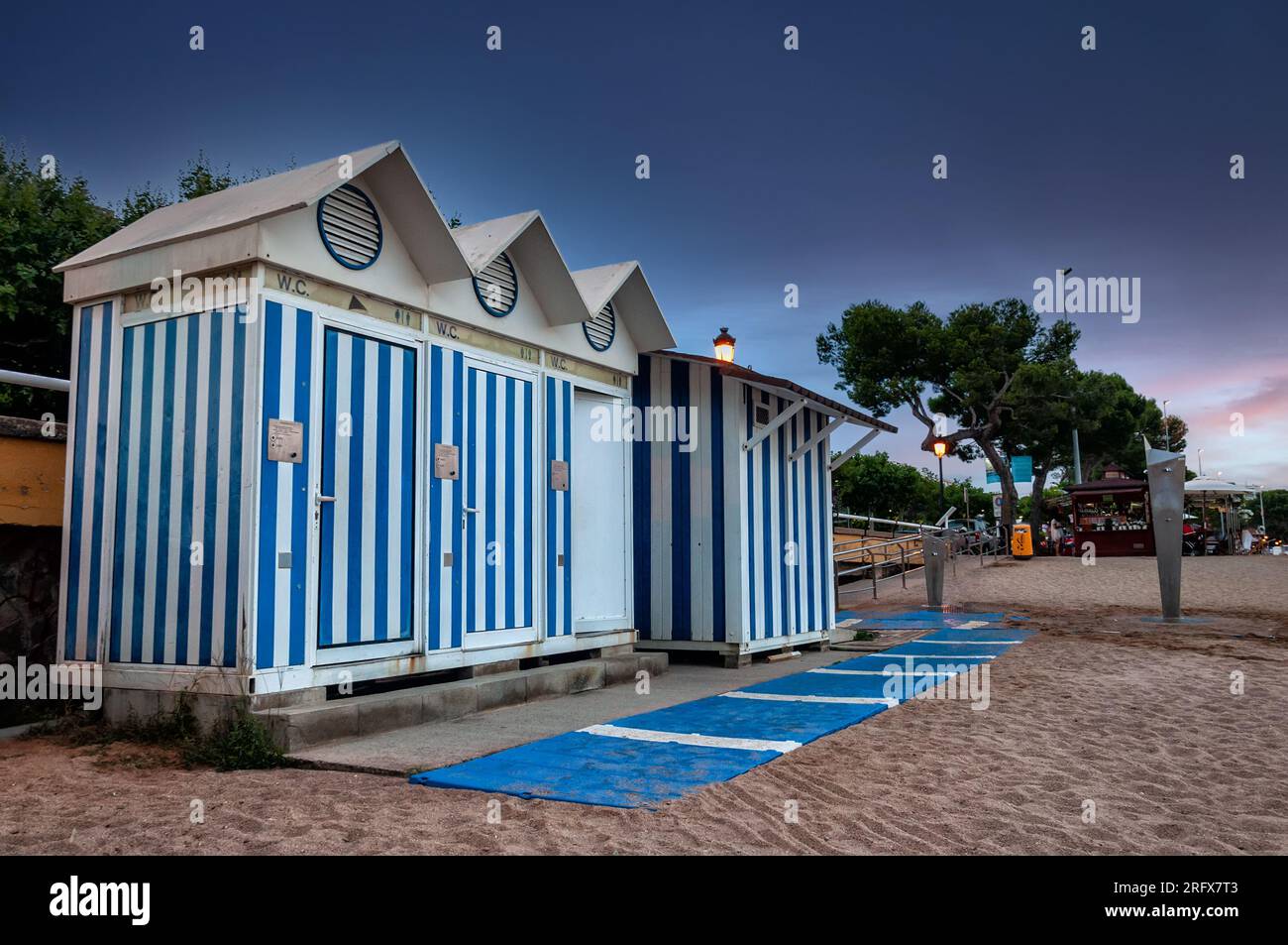 Bagno pubblico e cabina con strisce blu e bianche sulla spiaggia Foto Stock