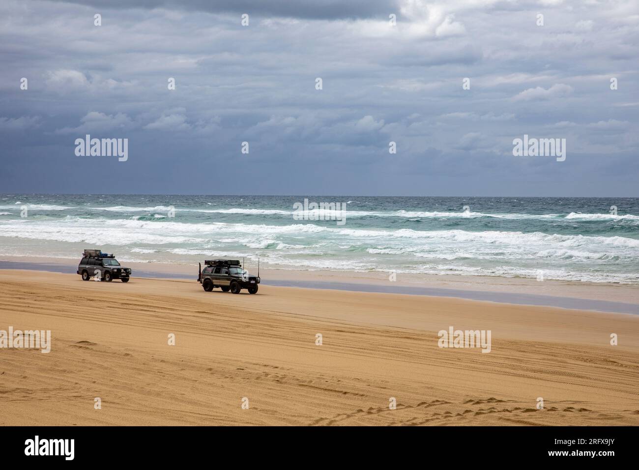 Fraser Island 4x4 guida su una spiaggia di 75 km circa, un veicolo 4x4 ne toglie un altro che si è rotto, Queensland, Australia Foto Stock