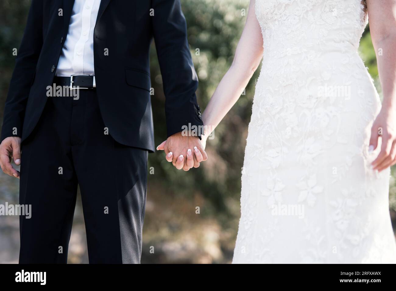 Ein Brautpaar hält sich die Hände Foto Stock