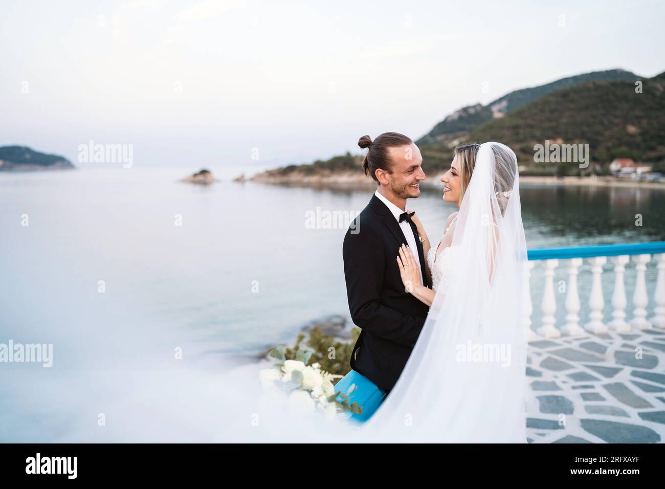Ein liebevolles Brautpaar genießt die Hochzeit mit Meeresblick Foto Stock