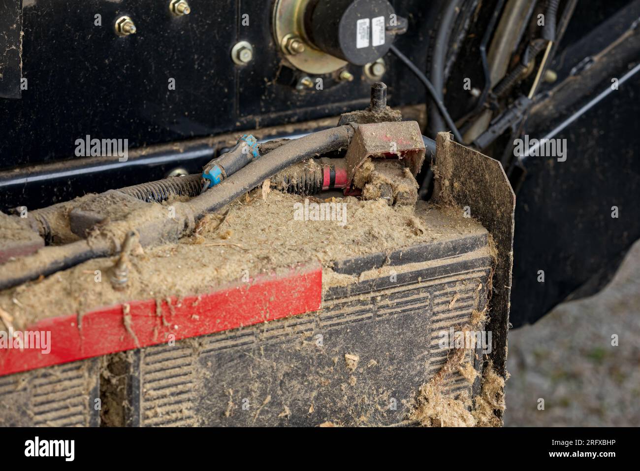 Batteria sporca sulla mietitrebbia. Concetto di riparazione, manutenzione e assistenza di attrezzature agricole e agricole Foto Stock